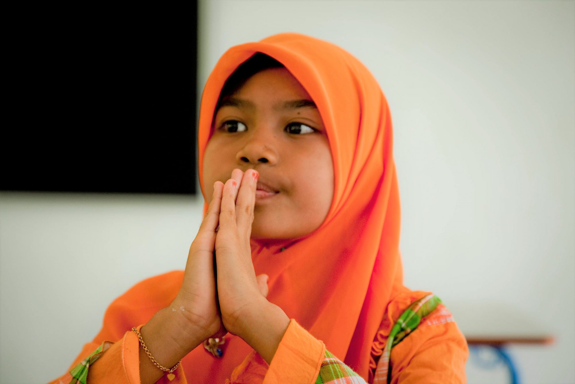 Young girl prayer with hands in front of her face.