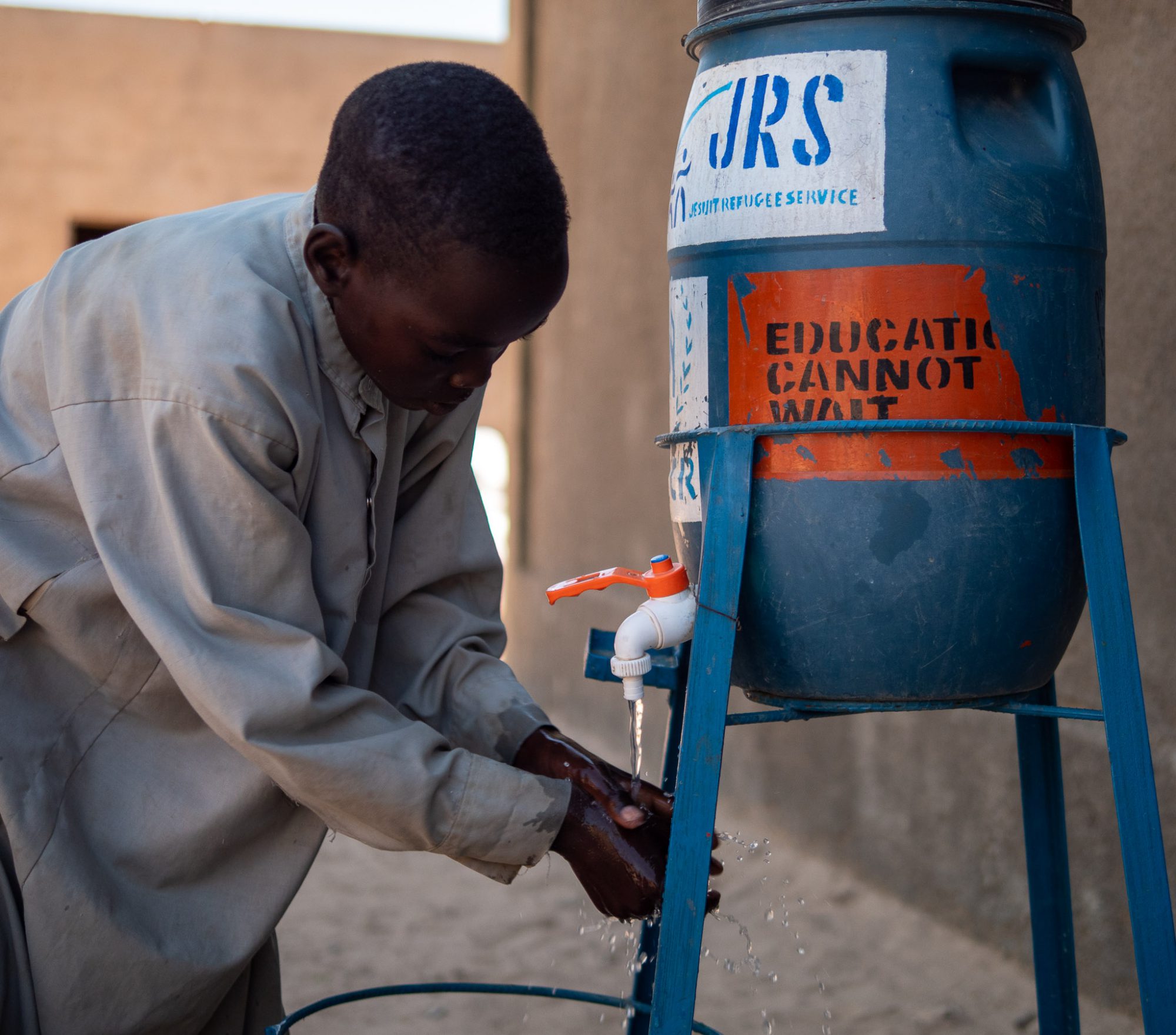 Boy using a hand-washing device to prevent the spread of Covid in the schools in kounougou refugee camp, Guereda.