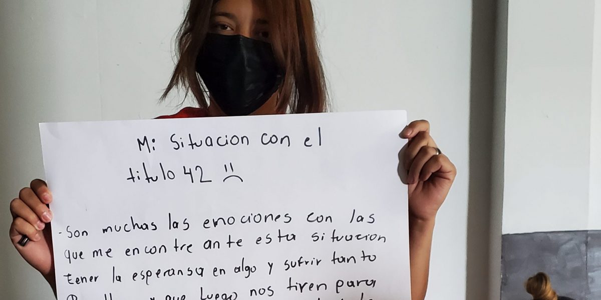 A woman wearing a mask holding a sign in Spanish.