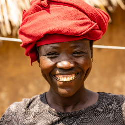 A women smiling at the camera wearing a red headdress.
